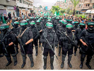 In this December 14, 2014, file photo, masked Palestinian gunmen of the Hamas militant grouphold weapons during a rally to commemorate the 27th anniversary of the group in Gaza City. Amnesty International on Wednesday, May 27, 2015, accused the militant group of abducting, torturing and killing Palestinians during the war in the Gaza Strip summer 2014, saying some of the actions amount to war crimes.