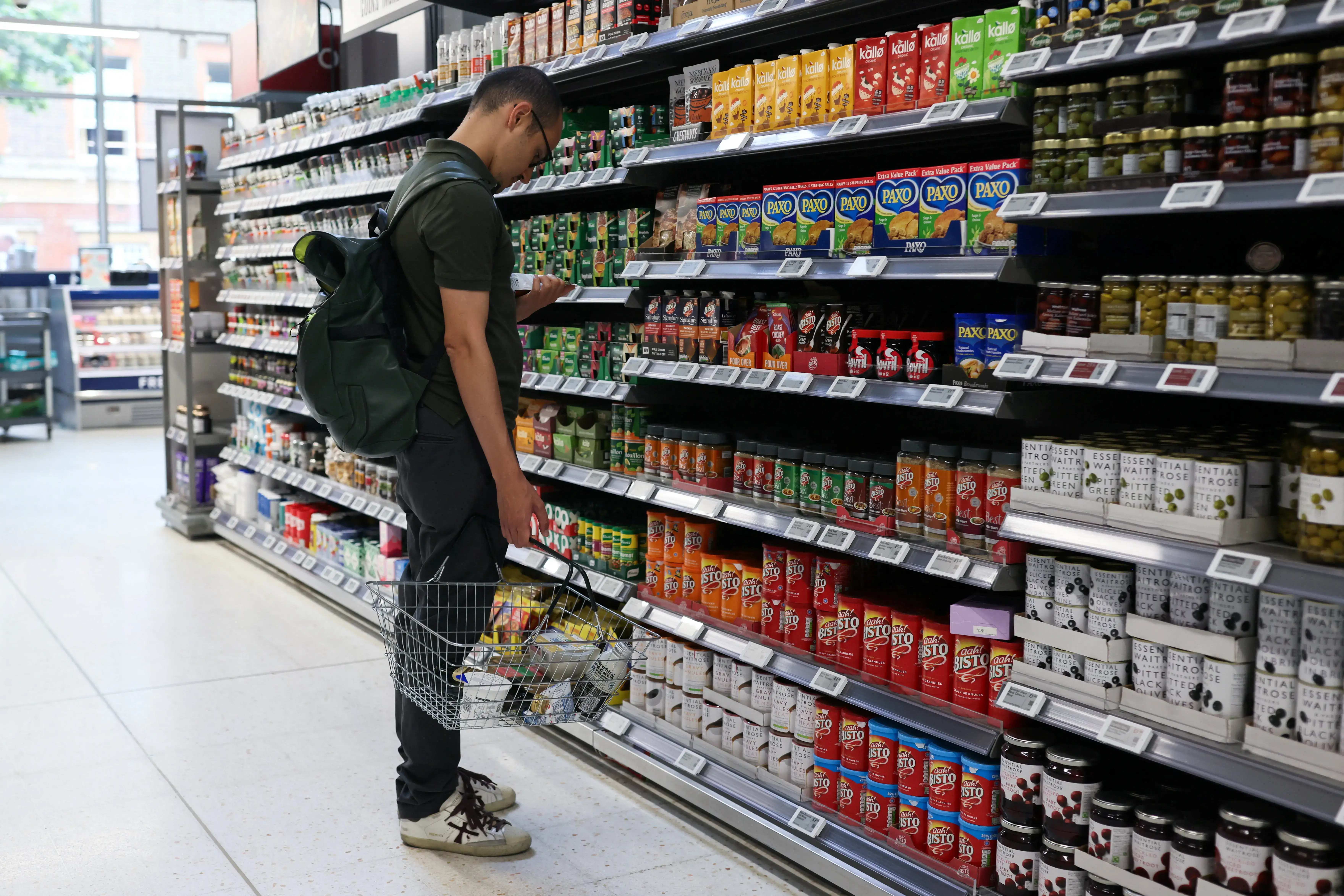 A shopper reads the packaging of an item in a supermarket in London