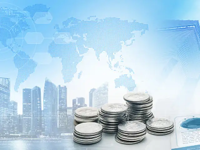 Picture of coins on table with background of a city and the world map representing finance all over the globe.