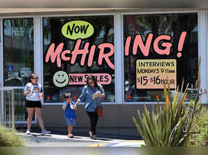 (FILES) In this file photo taken on July 08, 2022 a family walks past a "Hiring" sign at a McDonald's restaurant in Garden Grove, California. US job gains eased in March for a second straight month, government data showed March 7, 2023, adding to signs that the world's largest economy is cooling as policymakers push on in their fight against inflation. (Photo by Robyn BECK / AFP)