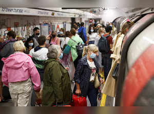 FILE PHOTO: People wearing protective face masks walk along a platform on the London Underground, amid the coronavirus disease (COVID-19) outbreak, in London