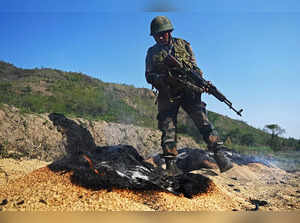 An Indian army soldier makes a scout as smokes rises from grains that was set on fire by a mob in the ethnic violence hit area of Senapati district in India's Manipur state on May 8, 2023. Around 23,000 people have fled the unrest which erupted last week in the hilly northeast state bordering Myanmar. The latest clashes erupted between the majority Meitei people, who are mostly Hindu, living in and around the Manipur capital Imphal and the mainly Christian Kuki tribe of the hills. (Photo by Arun SANKAR / AFP)