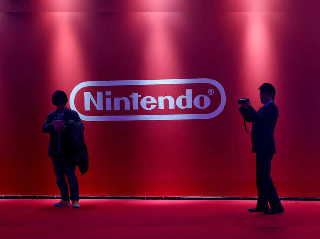 FILE PHOTO: People stand in front of Nintendo's logo at the presentation ceremony of its new game console Switch in Tokyo