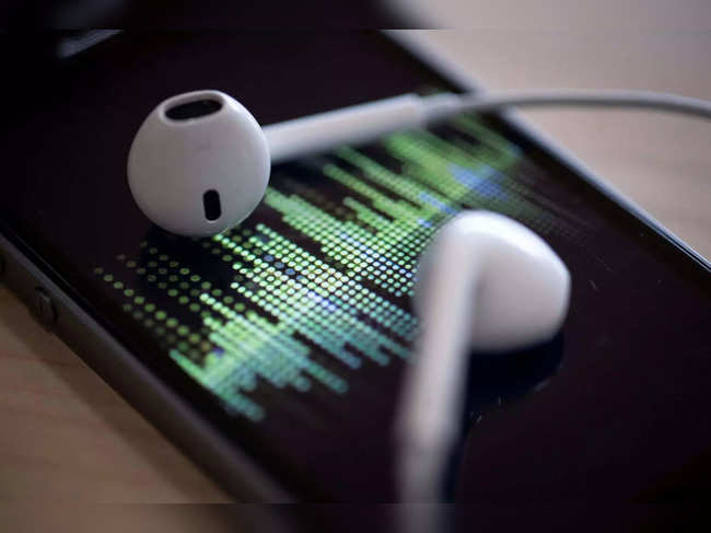 (FILES) A picture taken on February 8, 2019 in Paris shows a smartphone and its earphones as an audio podcast is being played. As people brace for the disruptive impact of artificial intelligence on jobs and everyday living, those in the world of audio books say their field is already being transformed.AI has the ability to create human-sounding recordings -- at assembly-line speed -- while bypassing at least part of the services of the human professionals who for years have made a living with their voices. (Photo by Thomas SAMSON / AFP)