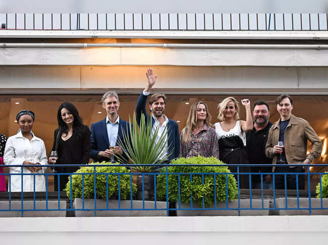 Swedish film director and President of the Jury of the 76th Cannes Film Festival Ruben Ostlund (4thL) waves to the crowd as he stands with members of the jury (from L) Zambian film director Rungano Nyoni, Moroccan film director Maryam Touzani, Argentinian film director Damian Szifron, US actress Brie Larson, French film director Julia Ducournau, French actor Denis Menochet and US actor Paul Dano on the balcony of the Grand Hyatt Cannes Hotel Martinez on the eve of the opening ceremony of the 76th edition of the Cannes Film Festival in Cannes, southern France, on May 15, 2023.  (Photo