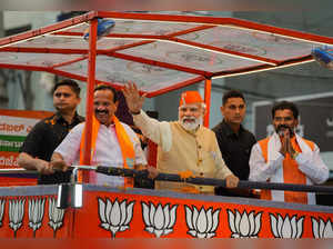 Bengaluru: Prime Minister Narendra Modi waves at crowd during a roadshow in supp...