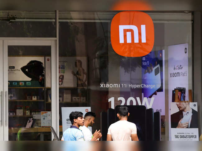 FILE PHOTO: People walk past Xiaomi, a Chinese manufacturer of consumer electronics, store in Mumbai