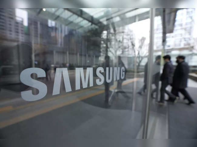Employees walk past a logo of the Samsung Electronics Co. at its office in Seoul...