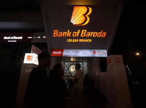 People walk past a branch office of Bank of Baroda in Mumbai