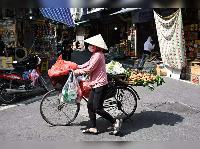 A street vendor pushes her bicycle carrying fruits in Hanoi on June 1, 2023. Thousands of street vendors, largely women, in Vietnam's capital have had no choice but to work through a series of heatwaves that have struck the north of the country in recent weeks.  - To go with 'VIETNAM-CLIMATE-ENVIRONMENT-ECONOMY,SCENE' by Tran Thi Minh Ha (Photo by Nhac NGUYEN / AFP) / To go with 'VIETNAM-CLIMATE-ENVIRONMENT-ECONOMY,SCENE' by Tran Thi Minh Ha