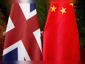 FILE PHOTO: A worker adjusts British and China national flags on display for a signing ceremony at the seventh UK-China Economic and Financial Dialogue "Roundtable on Public-Private Partnerships" in Beijing