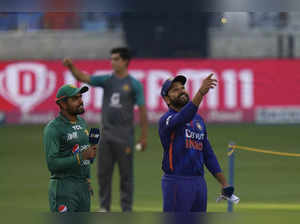Pakistan's captain Babar Azam, left, watches as India's captain Rohit Sharma spi...