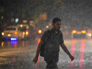 New Delhi: A man walks on a road amid rains, in New Delhi. (PTI Photo/Ravi Choud...