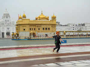 Amritsar: A child enjoys rain at the Golden Temple, in Amritsar. (PTI Photo)(...