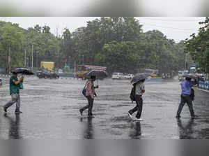 Kolkata: Pedestrians cross a road amid monsoon rain, in Kolkata. (PTI Photo)(...