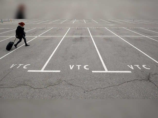 A woman walks past empty parking spots for ride-hailing services at Barcelona's airport