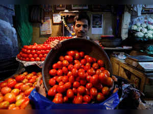FILE PHOTO: A vendor loads tomatoes in a bag for a customer at a wholesale vegetable market in Mumbai