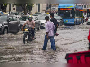 New Delhi: Commuters pass through a waterlogged road amid monsoon rains, in New ...