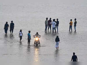 People wade along the banks of the Yamuna River as water levels rose due to moonsoon rains in Prayagraj on July 5, 2023. (Photo by SANJAY KANOJIA / AFP)