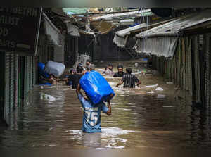 New Delhi: Locals wade through the flooded Monastery market following monsoon ra...