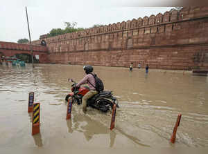 New Delhi: A motorcyclist wades through a flooded road near the Red Fort as the ...