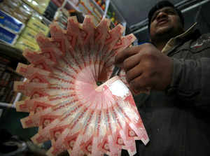 A shopkeeper holds a garland made of Indian currency notes inside his shop at Noida