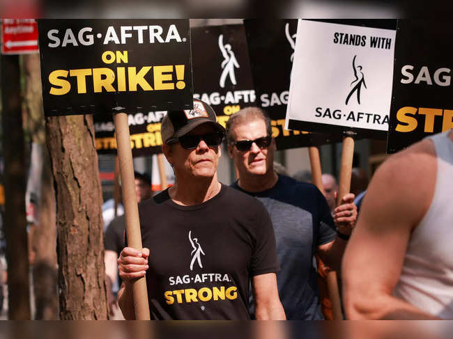 SAG-AFTRA actors and Writers Guild of America (WGA) writers walk while on strike outside NBC Studios in New York City