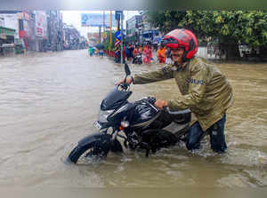 Haridwar: A motorist wades through a waterlogged road amid heavy monsoon rain, i...