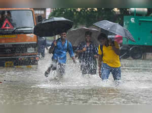 Mumbai: People wade through a waterlogged road amid monsoon rains, in Mumbai. (P...