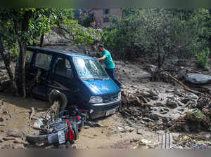 Kullu: A man looks at a van stuck in the debris following a cloud-burst at Kais ...