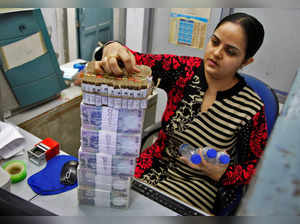 FILE PHOTO: A cashier stacks Indian currency notes inside a bank in Chandigarh