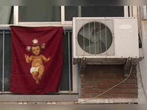 An air conditioner hangs on a wall next to a flag depicting a baby Jesus, in Malaga, southern Spain, on July 28, 2023. (Photo by JORGE GUERRERO / AFP)
