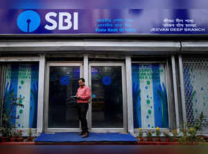FILE PHOTO: A man checks his mobile phone in front of a State Bank of India (SBI) branch in Kolkata