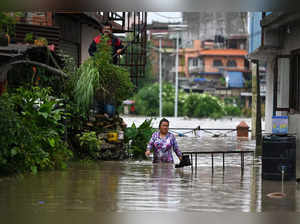 A woman wades along a flooded street in Kathmandu on August 8, 2023, after the Bagmati River overflowed following heavy monsoon rains. (Photo by PRAKASH MATHEMA / AFP)
