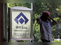 A man stands next to an advertisement of SAIL in New Delhi