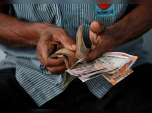 FILE PHOTO: An attendant at a fuel station arranges Indian rupee notes in Kolkata