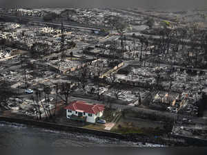 An aerial image shows a red roofed house that survived the fires surrounded by destroyed homes and buildings burned to the ground in the historic Lahaina in the aftermath of wildfires in western Maui in Lahaina, Hawaii on August 10, 2023. Embattled officials in Hawaii who have been criticized for the lack of warnings as a deadly wildfire ripped through a town insisted on August 16 that sounding emergency sirens would not have saved lives. At least 110 people died when the inferno levelled Lahaina last week on the island of Maui, with some residents not aware their town was