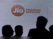 File photo of People standing next to a logo of Jio Financial Services ahead of its listing ceremony at the Bombay Stock Exchange in Mumbai