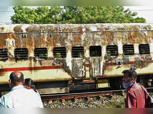 People walk past a damaged train coach parked at the Madurai railway yard after a fire broke out in the early hours of the morning, in Madurai on August 26, 2023. At least nine people were killed on August 26, after a train coach parked in southern India caught fire when a passenger tried to make tea, officials said. (Photo by AFP)