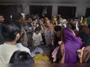 Relatives mourn as they gather around the body of a victim of train derailed inc...