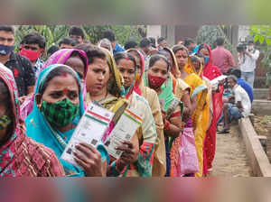 Khordha: Women show their identification card as they wait in a queue to cast th...