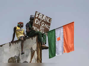 A man holds a placard and a Niger national flag as supporters of Niger's National Council of Safeguard of the Homeland (CNSP) protest outside the Niger and French airbase in Niamey on September 2, 2023 to demand the departure of the French army from Niger.