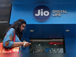 FILE PHOTO: A woman checks her mobile phone as she walks past a mobile store of Reliance Industries' Jio telecoms unit in Mumbai