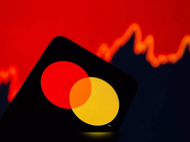 Smartphone with Mastercard logo is seen in front of displayed stock graph in this illustration