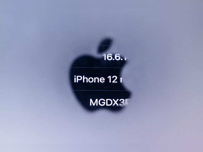 This illustration photograph taken on September 13, 2023 in Paris with a macro lens shows reversed information of an iPhone 12 reflected in the Apple logo of an iphone, as French regulators ordered Apple to halt sales of the iPhone 12 and to fix existing handsets for emitting too much electromagnetic radiation.