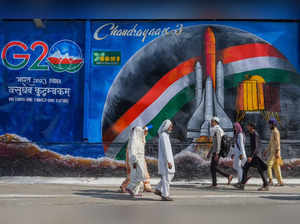 New Delhi: People walk past a mural depicting 'Chandrayaan-3' made on a garbage ...