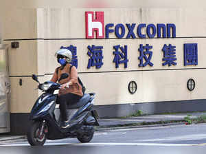 A woman drives past the logo of Foxconn outside the company's building in Taipei