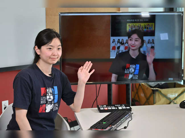 This picture taken on April 24, 2023 shows an engineer from artificial intelligence company Pulse9 conducting a demonstration as a live actor for virtual human Zaein, seen on-screen, during an interview with AFP at the company in Seoul.