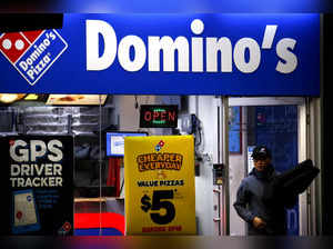 FILE PHOTO: FILE PHOTO: A worker carries a pizza for delivery as he exits a Domino's pizza store in Sydney, Australia