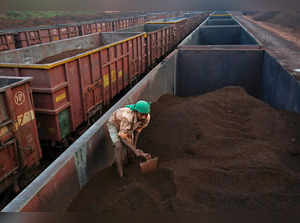 FILE PHOTO: A worker levels the iron ore in a freight train at a railway station at Chitradurga in Karnataka